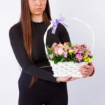 Devojka drži veselu korpu sa satiranim ružama, orhidejama i margaretama – Cvećara Nena