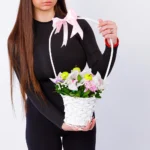 Devojka drži korpu sa roze orhidejama, margaretama, gipsofilom i jabukama – Cvećara Nena