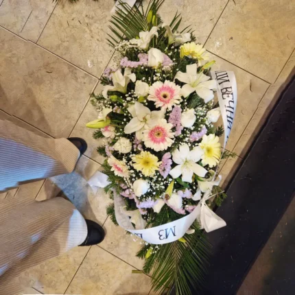 Cvetna suza od belih ljiljana, belih ruža i krem gerbera sa lila staticom – dostojanstven aranžman za poslednji oproštaj