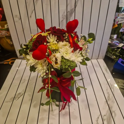 Detalj cvetnog boxa sa crvenim ružama i belim margaretama