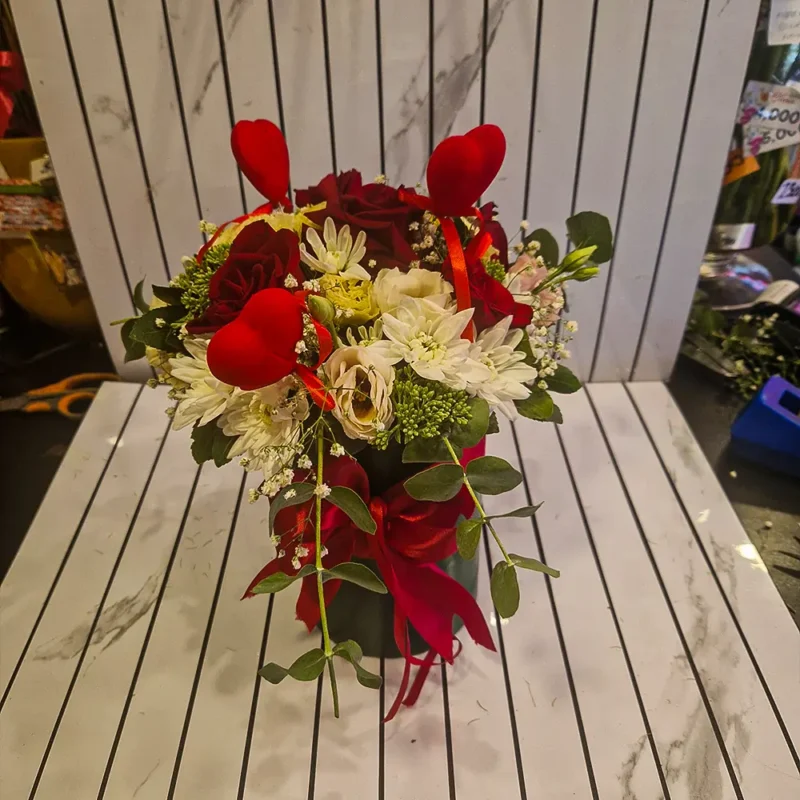 Detalj cvetnog boxa sa crvenim ružama i belim margaretama